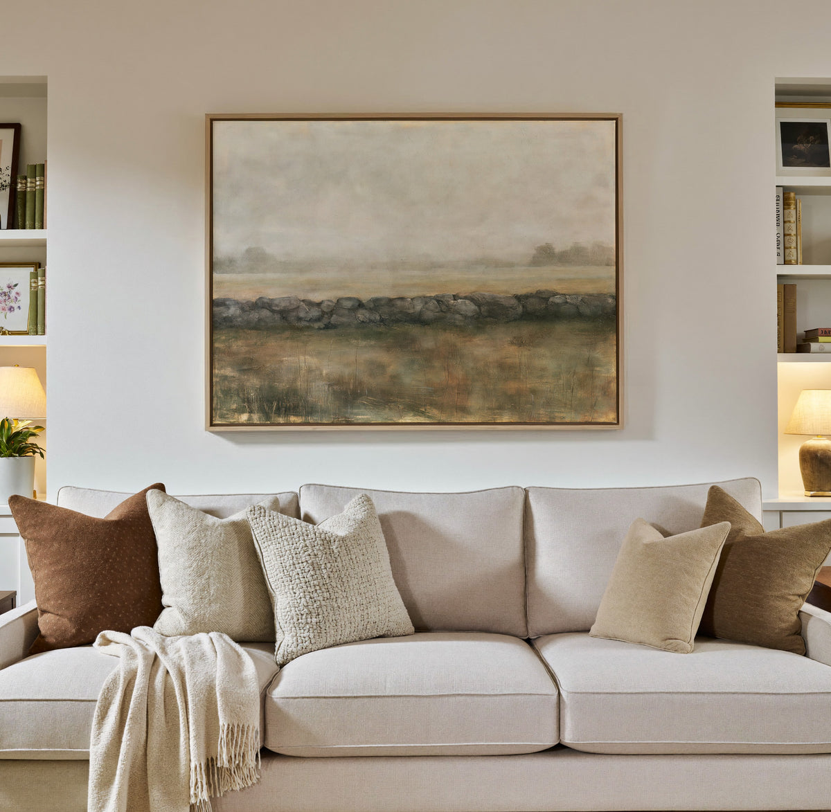 low stone wall across a hazy field canvas wall art in a natural wood frame in a styled room setting