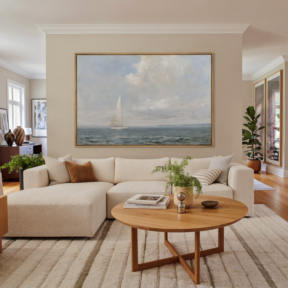 white sailboat beneath a pale oversized cloud canvas wall art in an oak frame in a living room