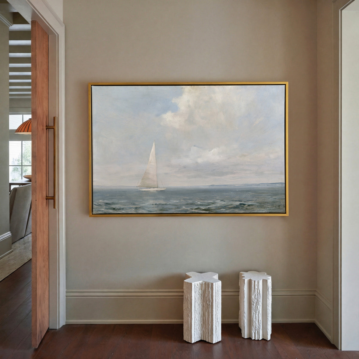 white sailboat beneath a pale oversized cloud canvas wall art in a gold frame in a styled room setting