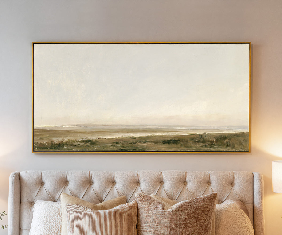 pale coastal landscape with low marshy ground canvas wall art in a gold frame above a bed