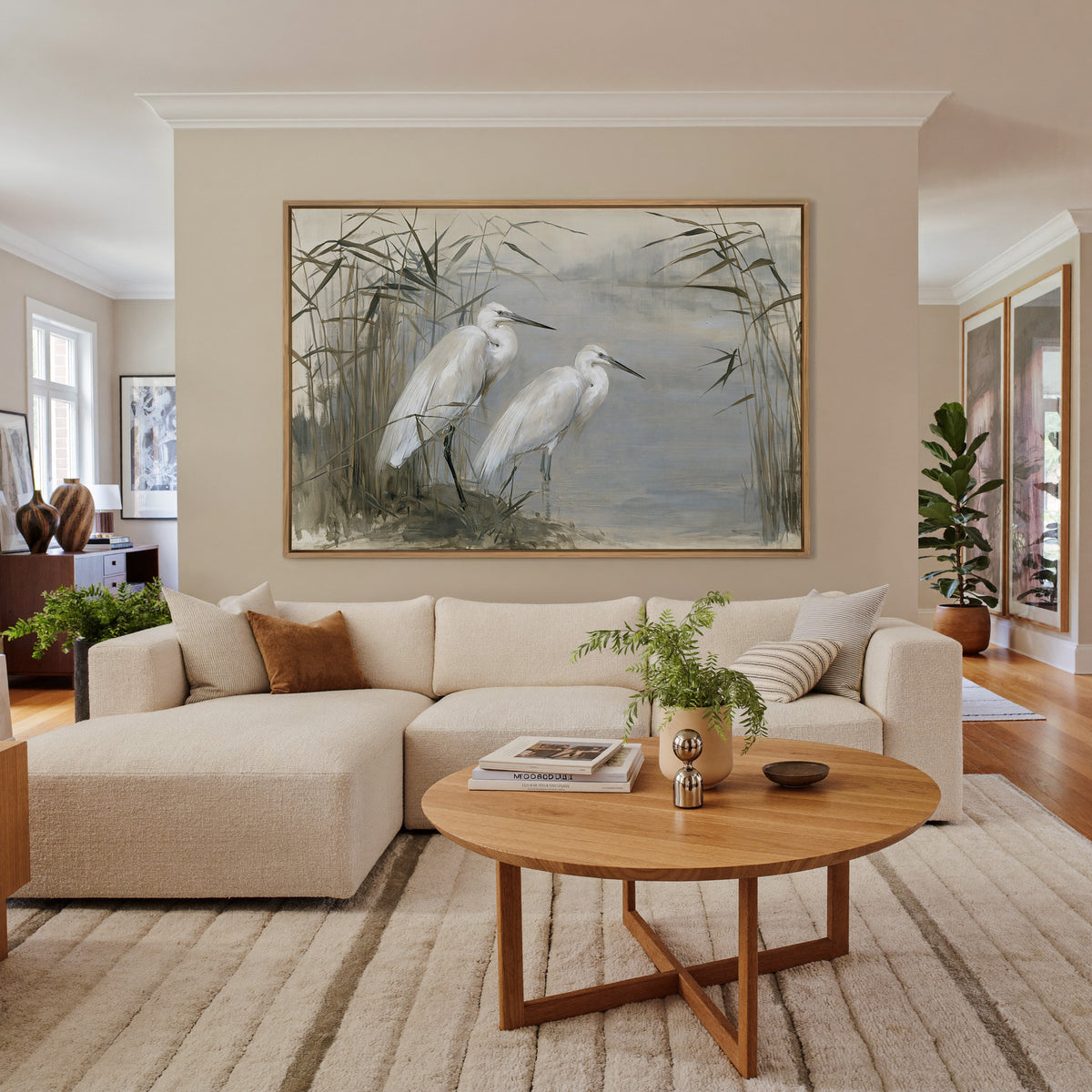 pair of white herons among tall reeds canvas wall art in an oak frame in a living room
