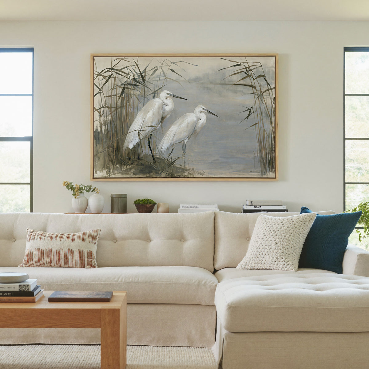 pair of white herons among tall reeds canvas wall art in a natural wood frame in a living room