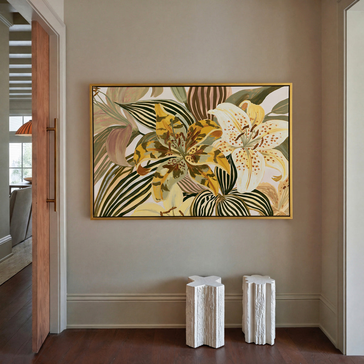 oversized yellow and cream tiger lilies among canvas wall art in a gold floater frame in a styled room setting