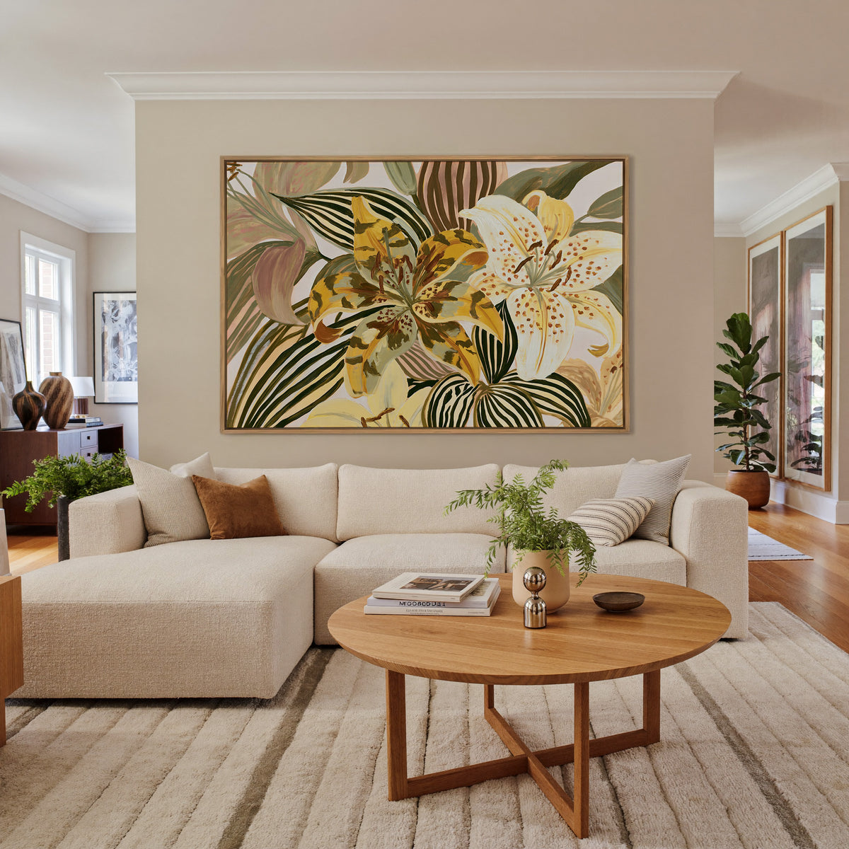 oversized yellow and cream tiger lilies among canvas wall art in an oak finish floater frame in a living room