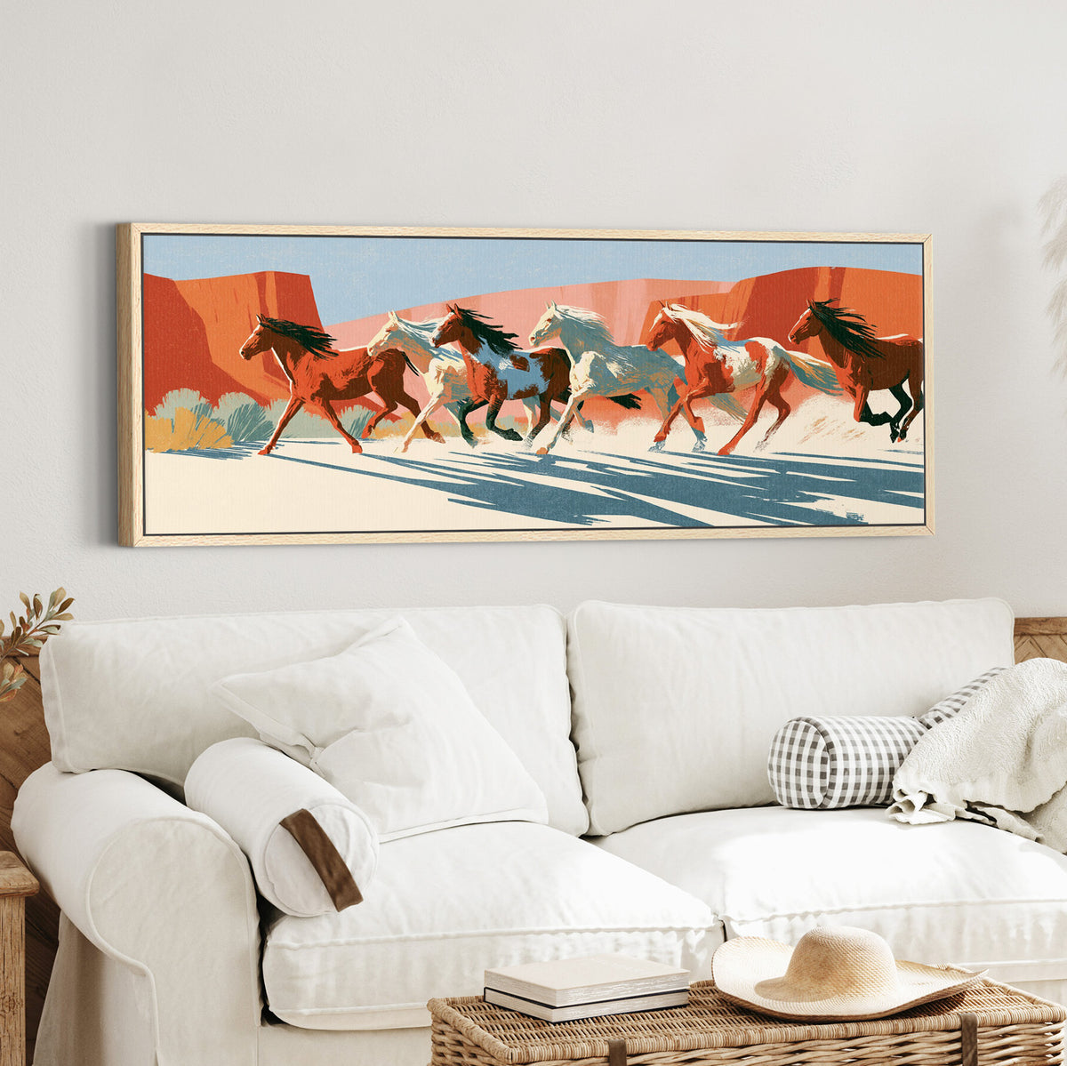running horse herd beneath canvas wall art in an oak finish floater frame in a styled room setting