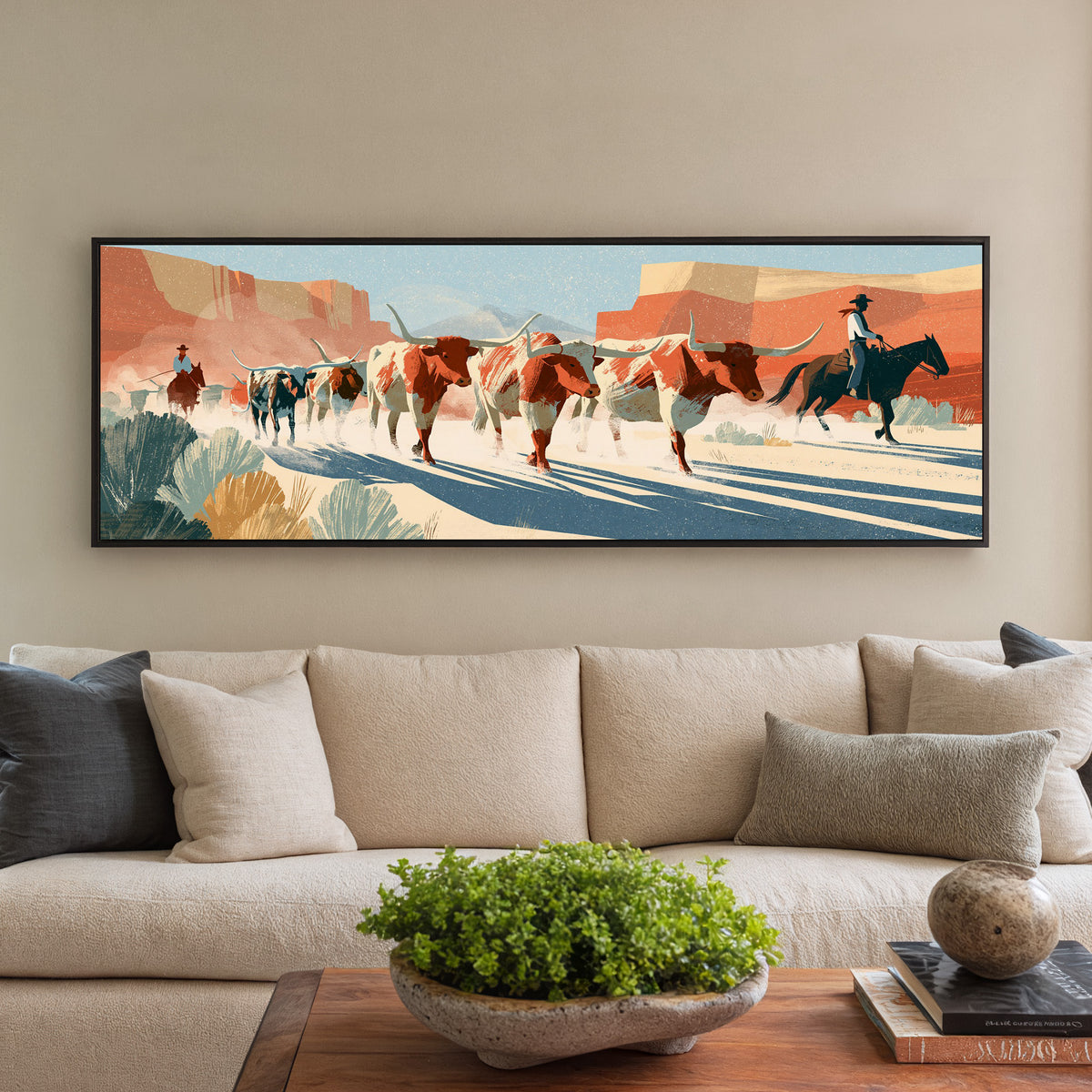 longhorn cattle and mounted riders beneath canvas wall art in a black floater frame in a styled room setting