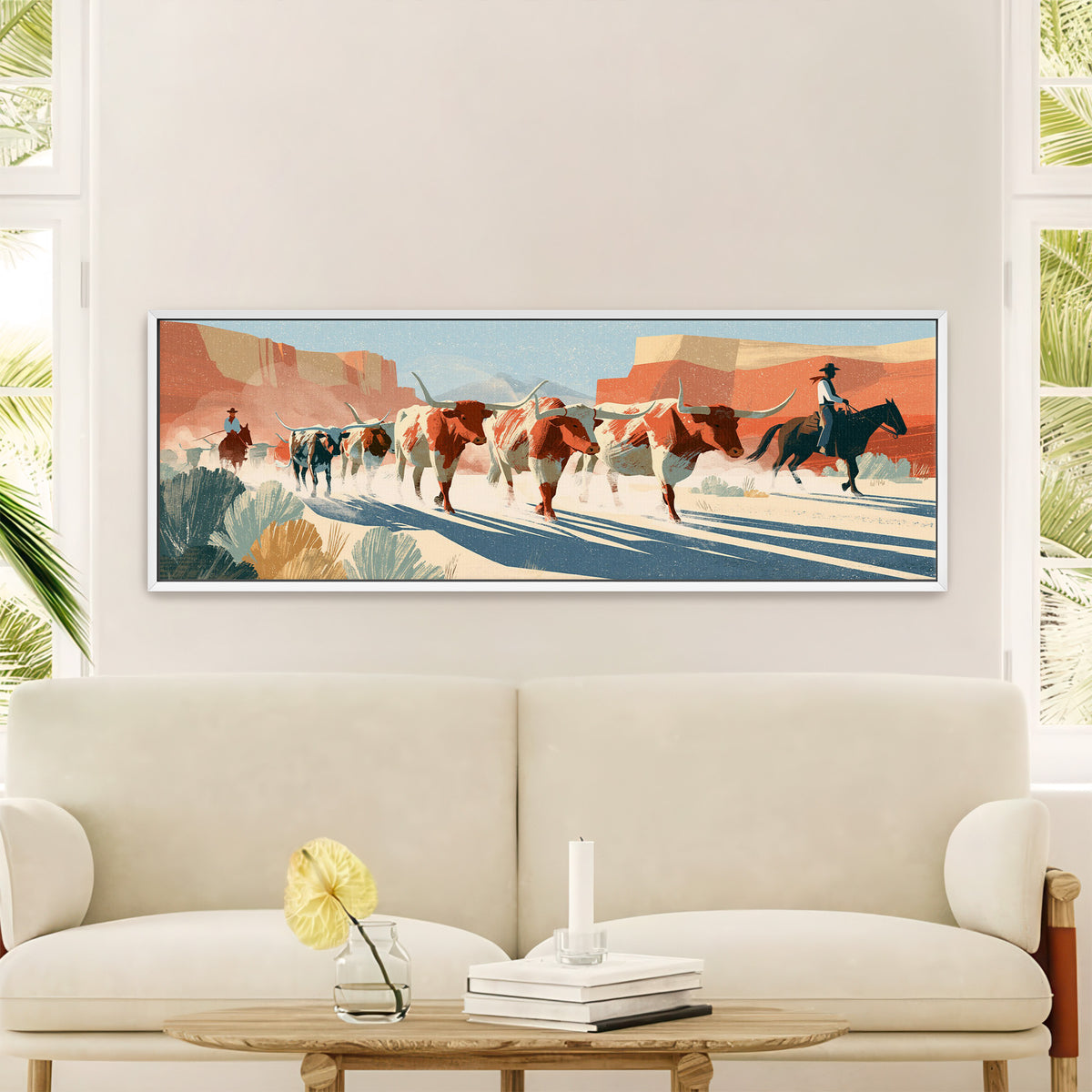 longhorn cattle and mounted riders beneath canvas wall art in a white floater frame in a styled room setting