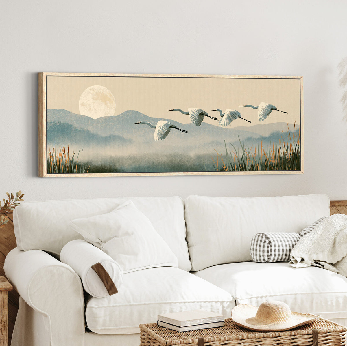 four white egrets flying above canvas wall art in an oak finish floater frame in a styled room setting