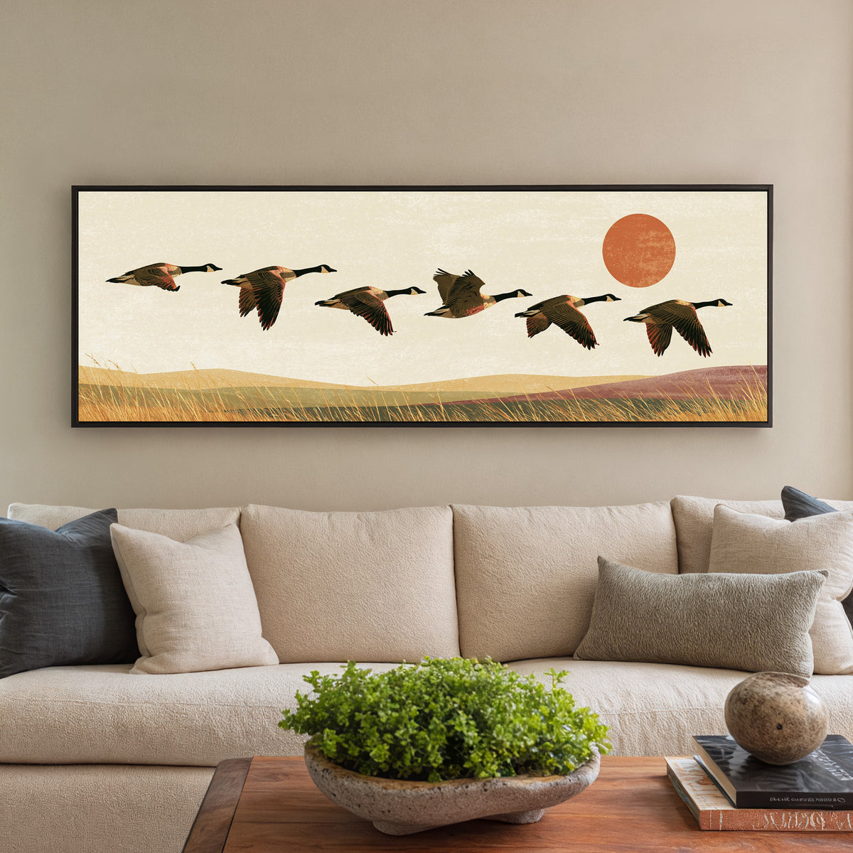 six canada geese flying over golden grass canvas wall art in a black floater frame in a styled room setting