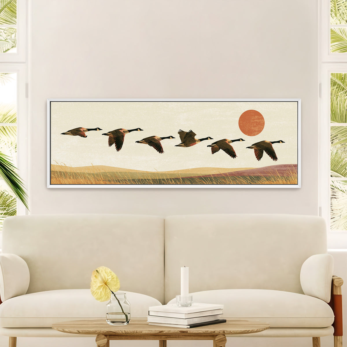 six canada geese flying over golden grass canvas wall art in a white floater frame in a styled room setting