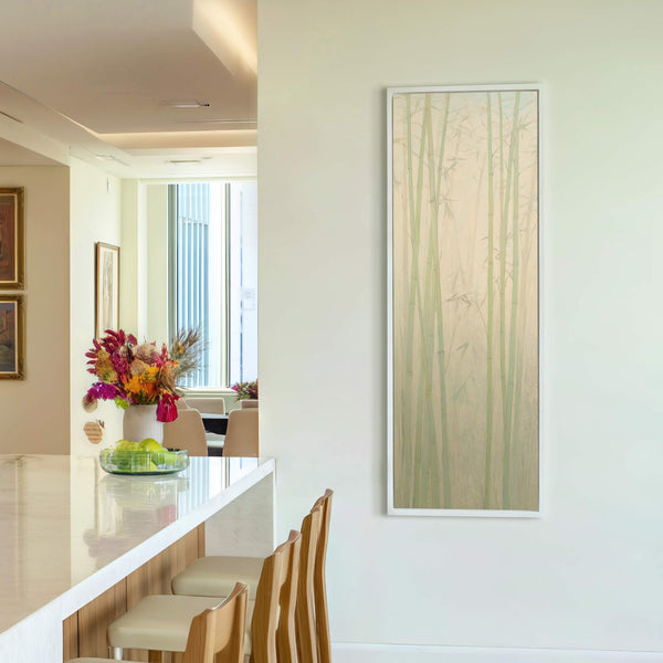 This vertical canvas print features a minimalist bamboo forest in pale green and beige tones, framed in white and displayed on a light-colored wall, near a bar with counter stools.
