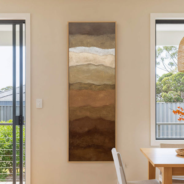 This abstract art print features horizontal layers in earthy brown and sandy tones, with a touch of white. It is a vertical canvas print with a natural wood floater frame.