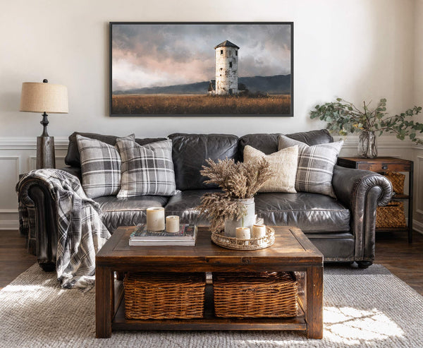 This horizontal, landscape canvas print features an impressionistic painting of an old, weathered tower in a field under a dramatic, cloudy sky. The artwork has a black floater frame and.