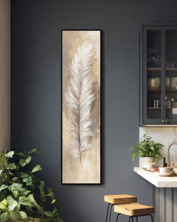 This vertical impressionistic painting print of a white feather in a neutral palette hangs in a black floater frame on a charcoal kitchen wall near a lush green plant.