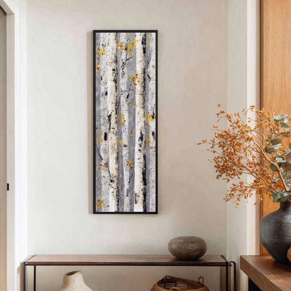 This vertical canvas wall art features an abstract impressionist style with a palette of grays, whites, and yellow accents, depicting birch trees. It is displayed on a light-colored wall above.