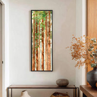 A vertical watercolor art print depicts a forest of redwood trees with a palette of earthy browns and vibrant greens, framed in black and displayed on a white wall above.