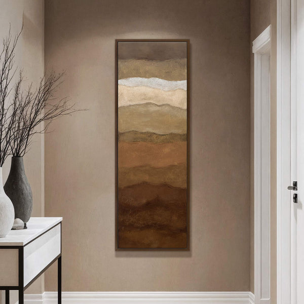 This vertical abstract landscape art print uses a warm, earthy palette of browns and creams, depicting layered hills or strata. It is framed in a natural wood floater frame and.