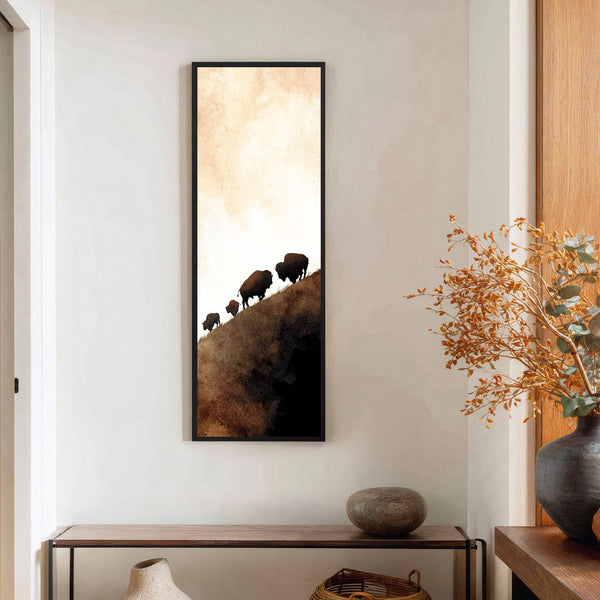 This vertical canvas print features a minimalist watercolor style with a palette of earthy browns and creams, depicting silhouettes of bison ascending a hill. It is displayed on a white.