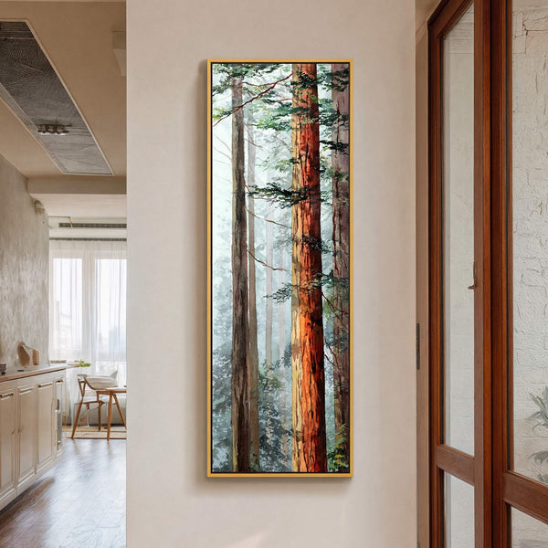 This vertical canvas wall art features a watercolor painting of a forest with tall trees and lush green foliage, framed in gold and displayed on a beige wall in a.