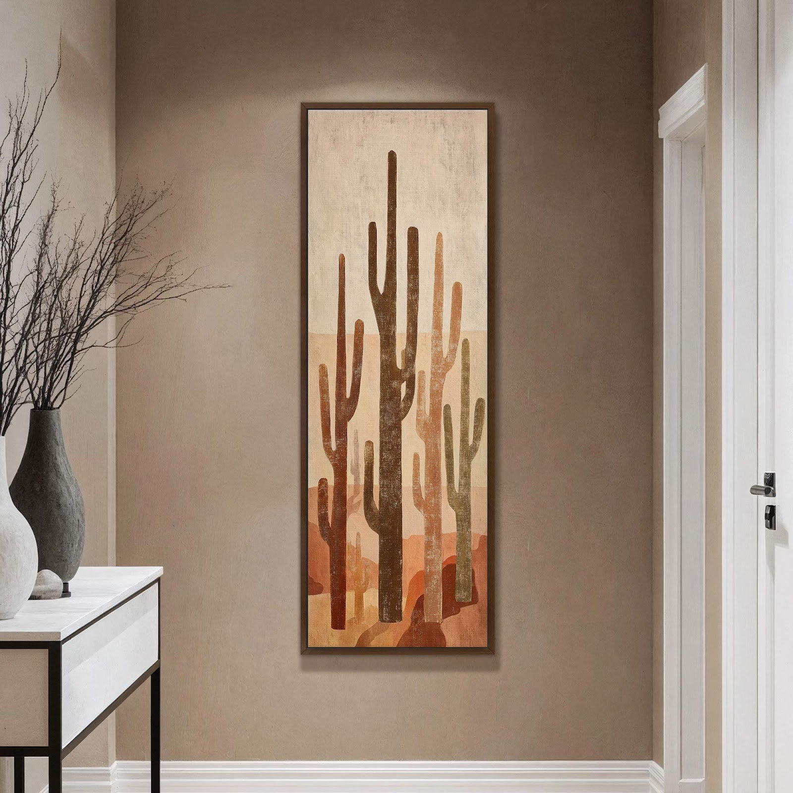 This vertical canvas wall art features a desert landscape with saguaro cacti in muted earth tones, set against a beige textured background and framed in dark wood, hanging on a.