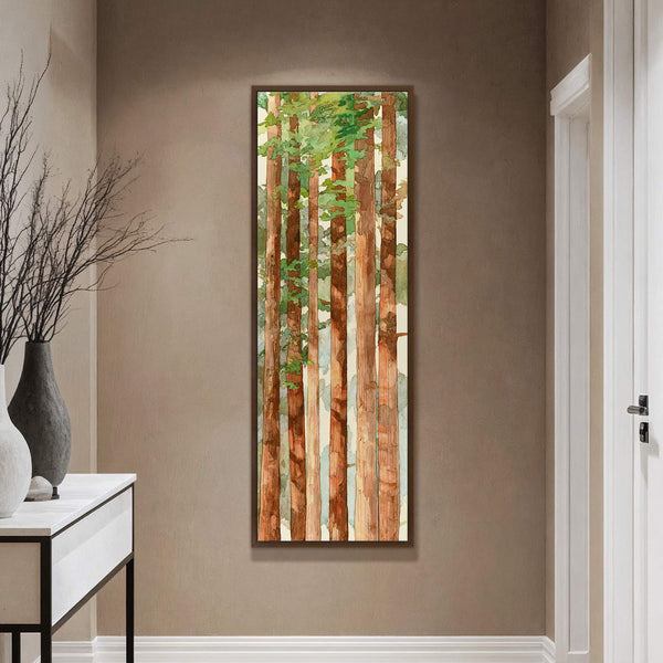 This vertical watercolor art print depicts redwood trees with a palette of greens and browns, framed in dark walnut, hanging on a taupe wall above a console table with vases.