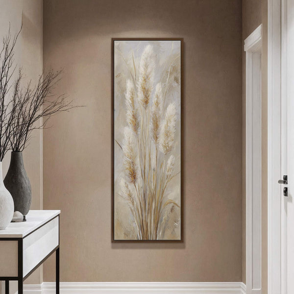 This vertical canvas wall art features a neutral palette and impressionistic style, depicting tall pampas grass plumes in a hallway with a console table and vases.