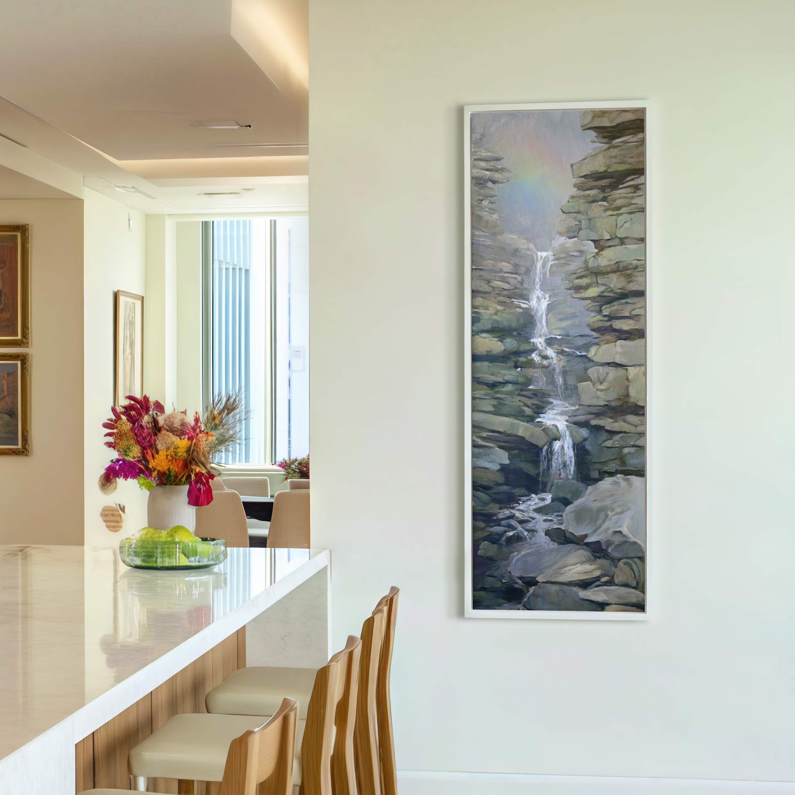 This vertical canvas wall art depicts a waterfall cascading over rocky cliffs in a cool palette, framed by a thin white floater frame, hung on a neutral wall in a.