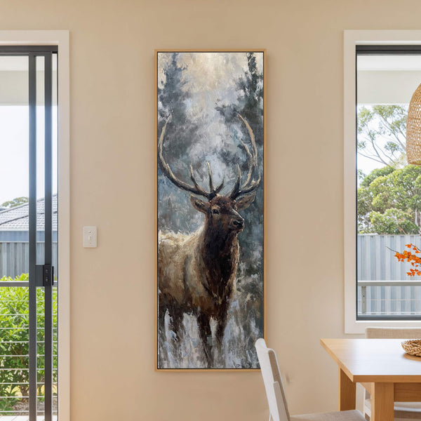 This vertical, impressionistic art print depicts a majestic elk with large antlers standing amidst a misty forest. The artwork, featuring a muted palette of browns and blues, is framed in.