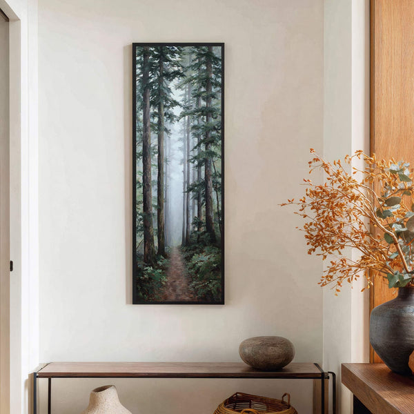 A vertical canvas wall art print depicts a foggy forest path with tall trees and lush greenery, rendered in a realistic style with a muted green and brown palette. It.