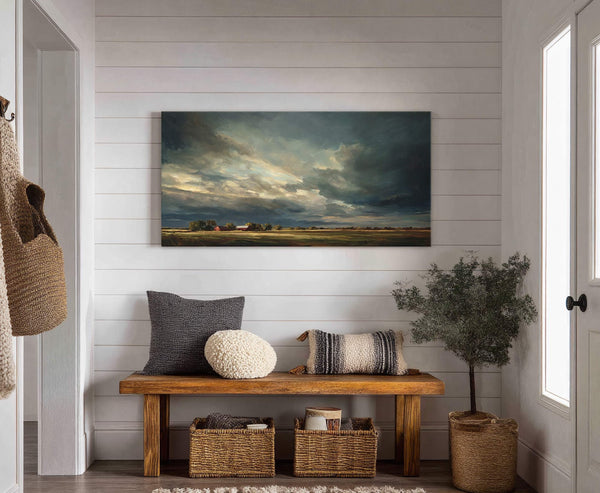 A horizontal canvas wall art depicts a moody, stormy sky over a rural landscape with red barns, rendered in dramatic brushstrokes and a dark, earthy palette, displayed on a white.