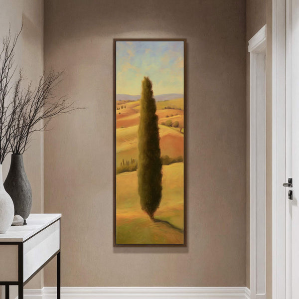 This vertical canvas wall art features a landscape painting with a tall, dark cypress tree as the subject, rendered in a warm, impressionistic palette. It is displayed on a brown.