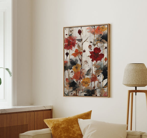 Pecan framed abstract floral art print featuring expressive red, orange, yellow, and black flower shapes and stems on a textured white background, hung on a light wall above a sofa.