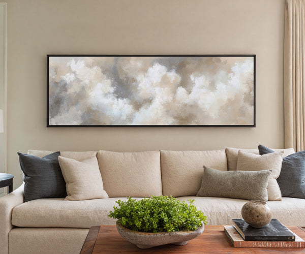 Beige sofa with decorative pillows in a living room setting, featuring a large abstract wall art piece.