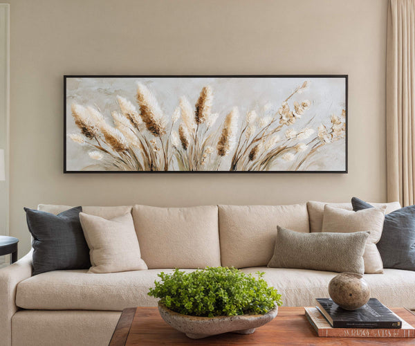 Framed pampas grass canvas wall art displayed above a beige sofa with neutral pillows in a modern living room interior