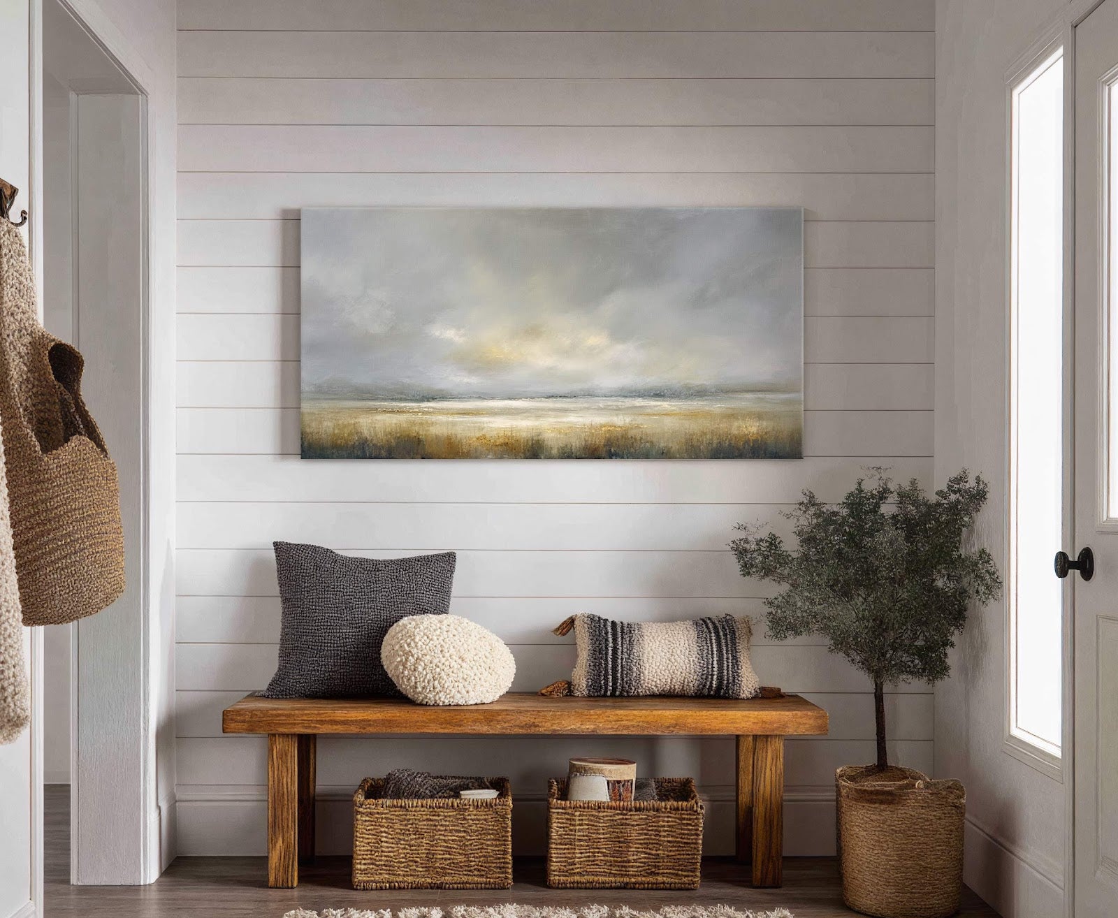 This horizontal canvas print features a hazy landscape with a muted palette of grays, whites, and warm earth tones. It hangs above a wooden bench in a room with white.
