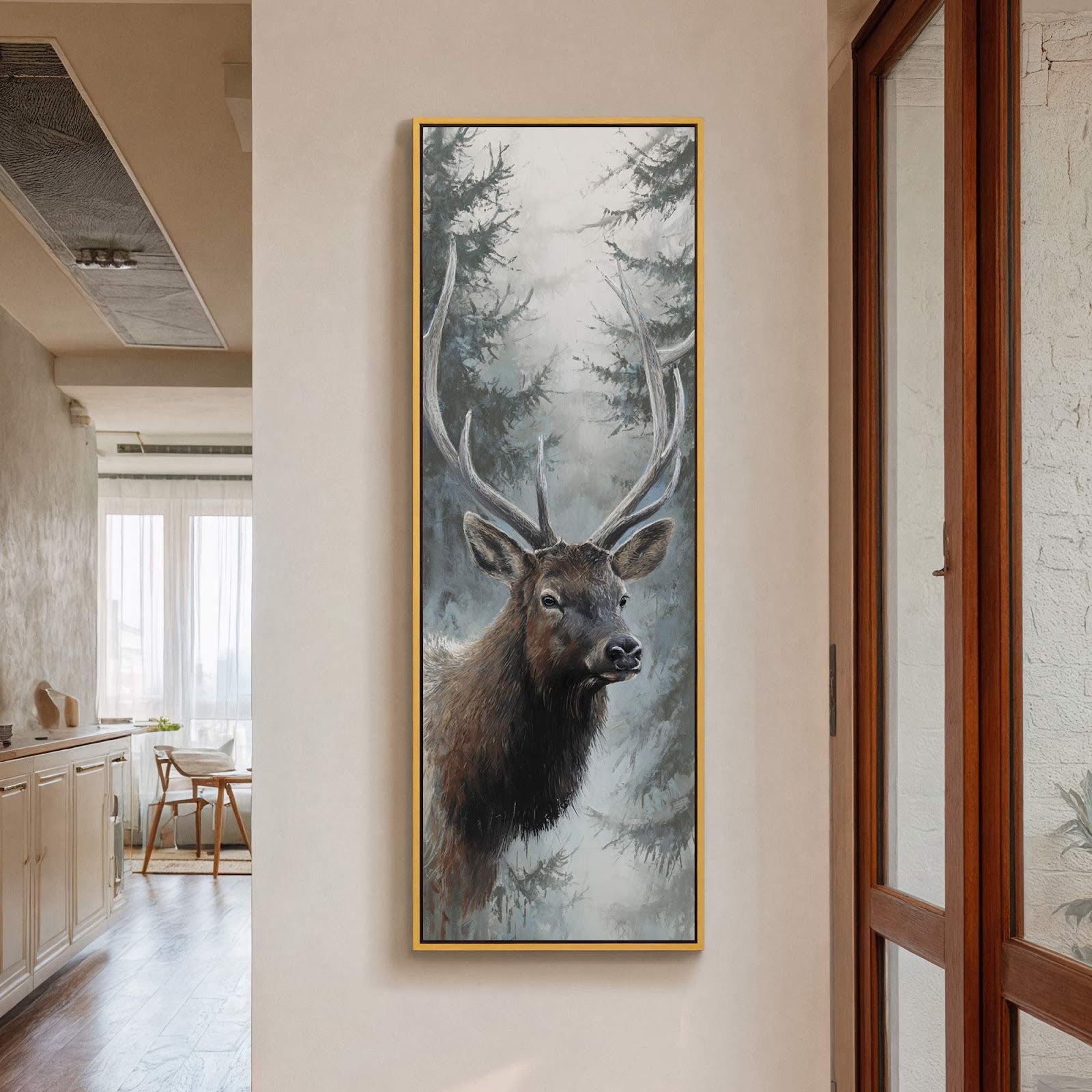 This vertical, impressionistic art print depicts a majestic stag with large antlers emerging from a misty, gray forest, framed in gold and displayed on a neutral wall near a wooden.