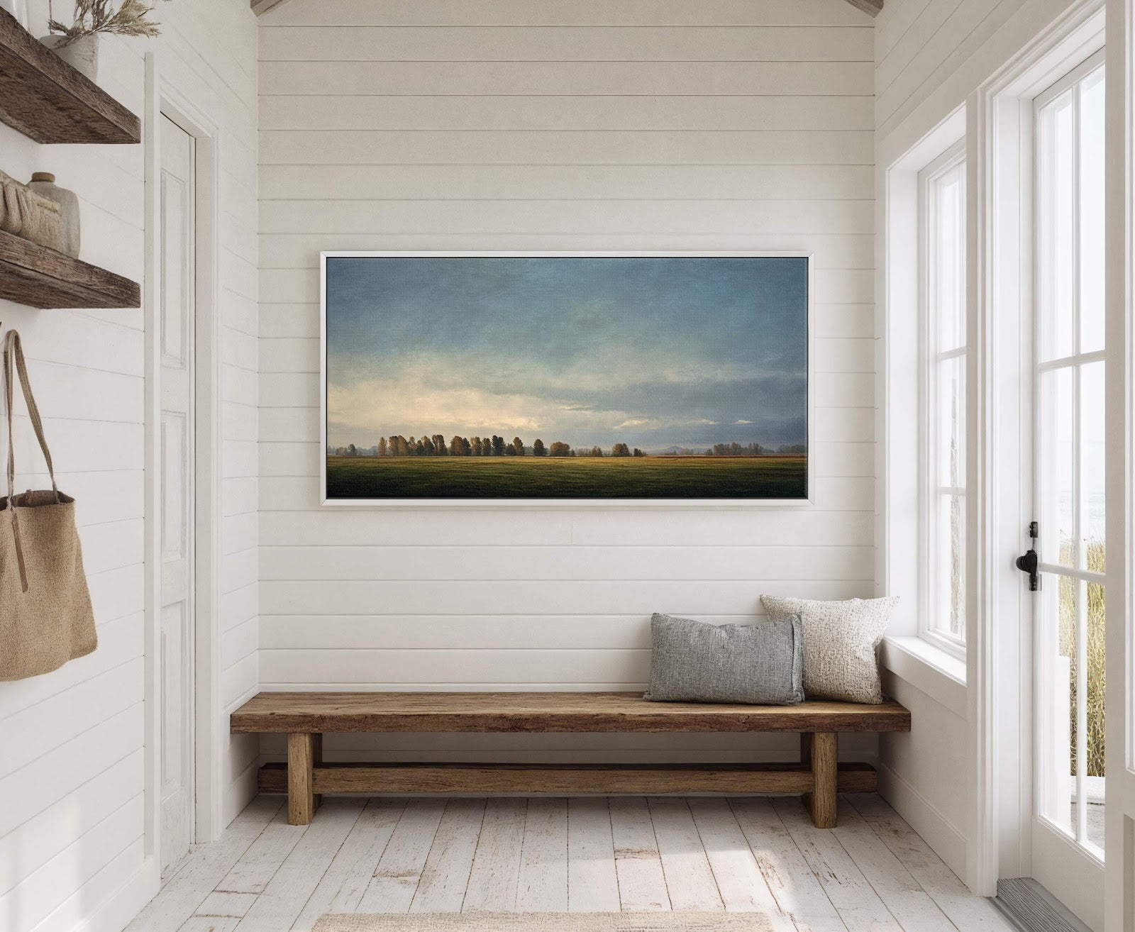 This horizontal canvas wall art features a hazy landscape with trees under a soft blue and yellow sky. It is displayed on a white shiplap wall above a rustic wooden.