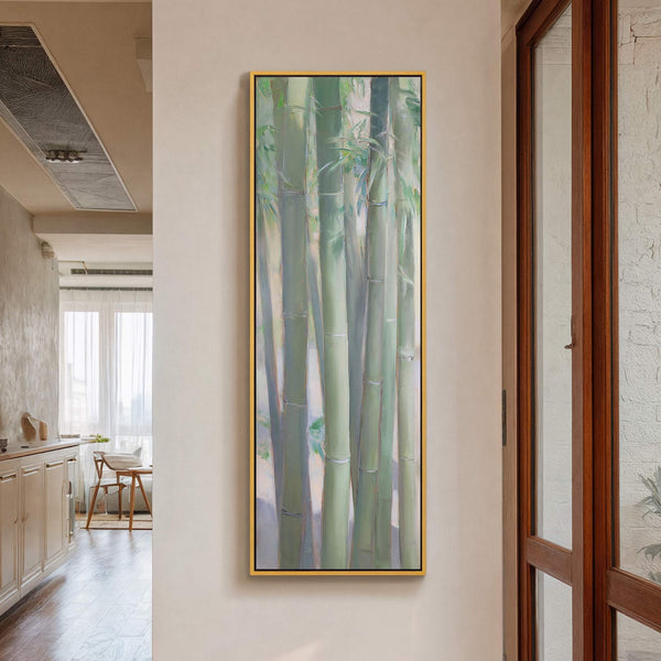 This vertical canvas print features a painterly style with a palette of soft greens and blues, depicting bamboo stalks. The artwork is framed in gold and hangs on a light-colored.