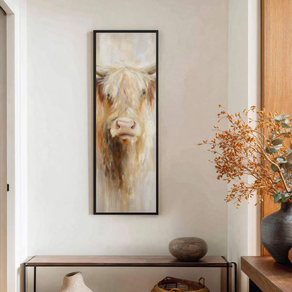 This vertical, impressionist painting print features a Highland cow portrait in warm, earthy tones, framed in black, and displayed above a wooden console table against a white wall.