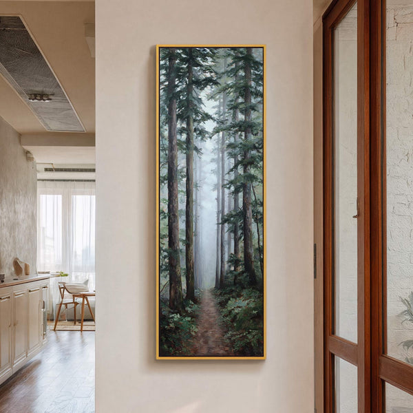 This vertical canvas wall art depicts a misty forest path with tall trees in a realistic style and a dark green and brown palette, framed in gold and hanging on.