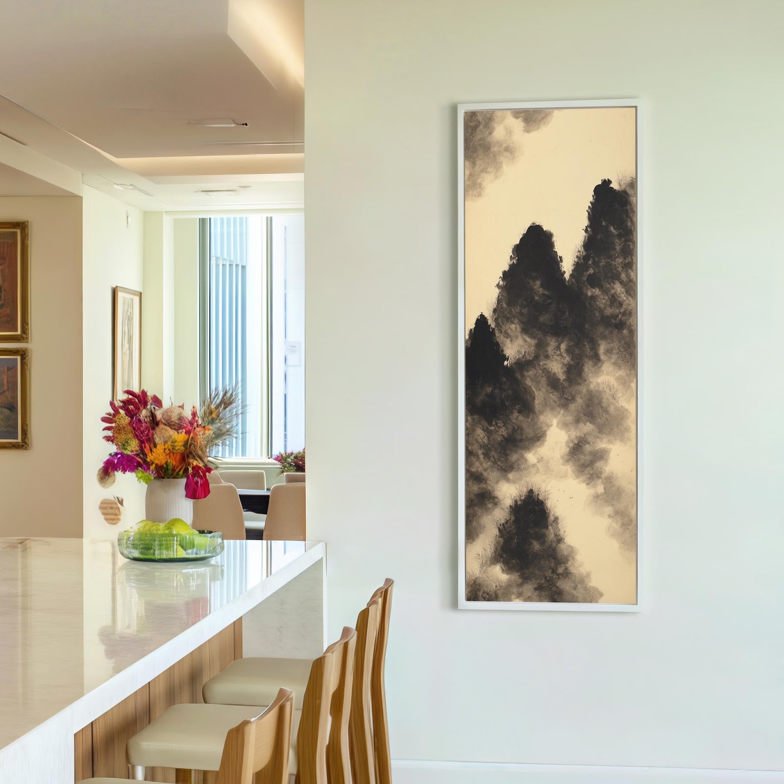 This vertical art print depicts monochromatic ink wash mountains in a white floater frame, displayed on a cream wall in a kitchen beside a marble-topped breakfast bar.