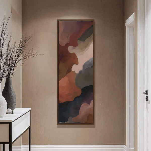This vertical canvas wall art features an abstract organic design in a warm palette of rust, brown, and grey, displayed on a textured tan wall above a console table with.