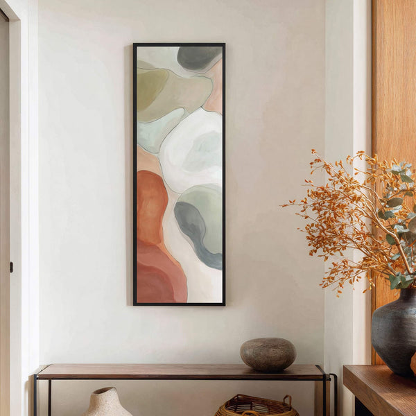 This vertical canvas wall art features an abstract design with organic shapes in a palette of terracotta, sage green, and cream, framed in black and displayed on a light-colored wall.