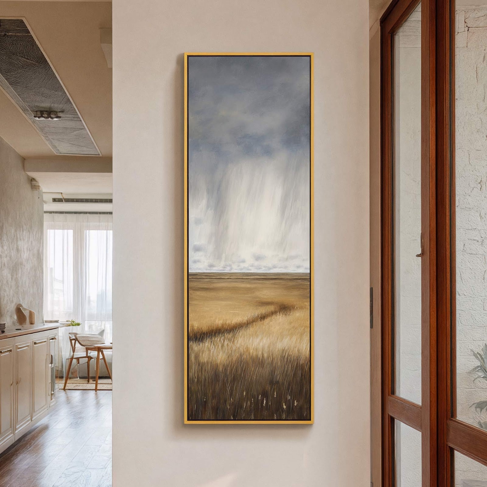 This vertical canvas print depicts a stormy sky over a golden field in a realistic style. It is displayed on a neutral wall next to a wooden door frame, with.