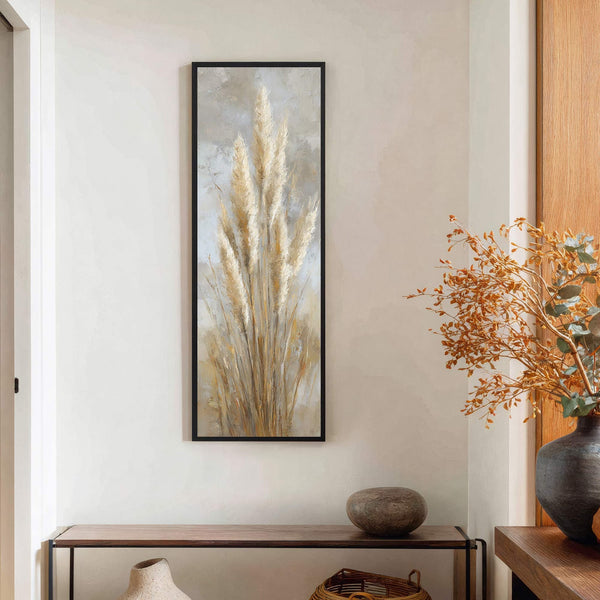 This vertical canvas wall art features a painterly depiction of tall, golden pampas grass against a textured, neutral background, framed in black, and displayed on a light-colored wall above a.