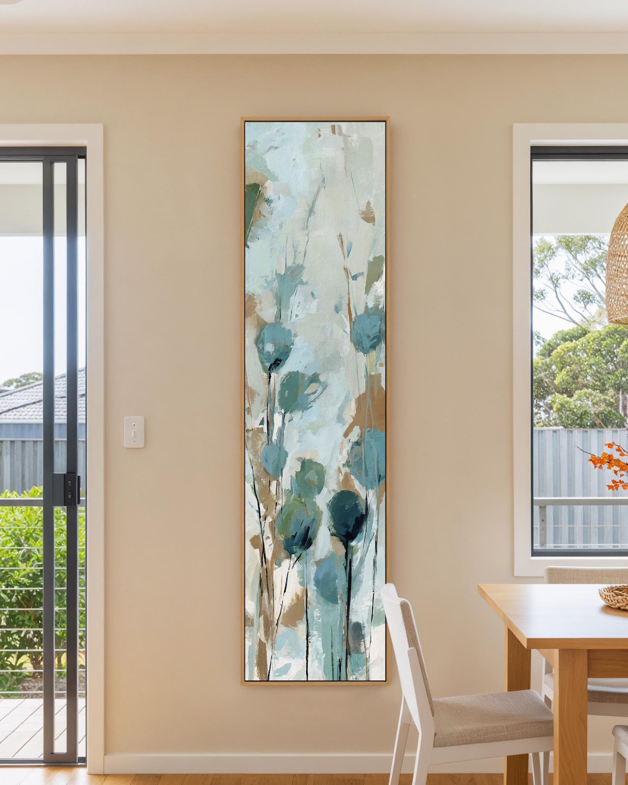 Teal wildflower botanical canvas print in natural floating frame above dining table in bright modern kitchen, vertical wall art for dining room