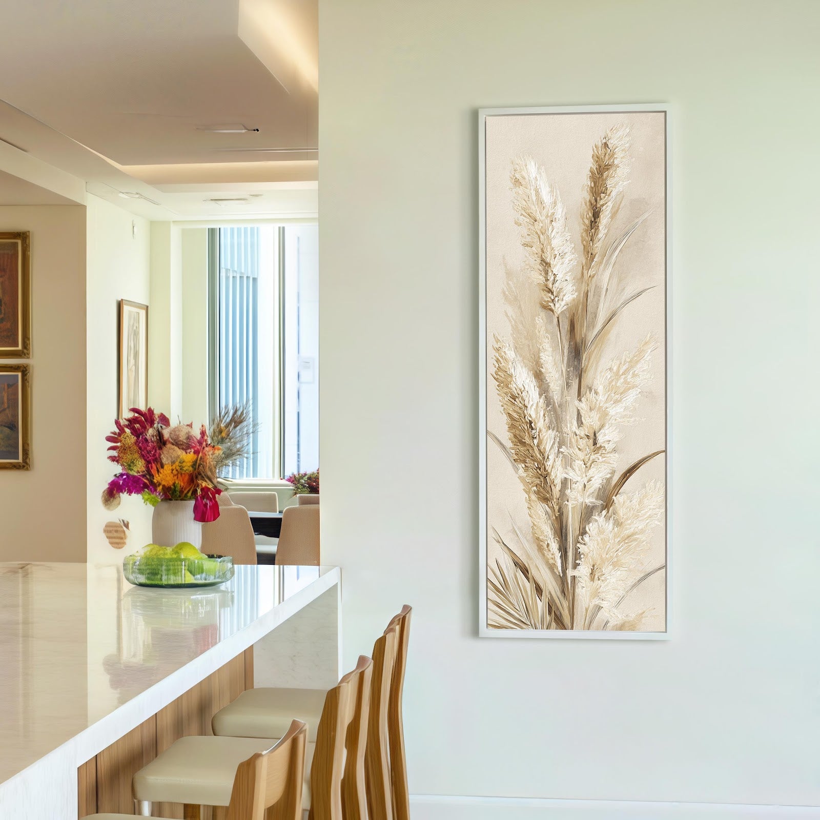 This vertical botanical art print of textured cream pampas grass in a white floater frame is displayed on an off-white kitchen wall beside a marble counter.
