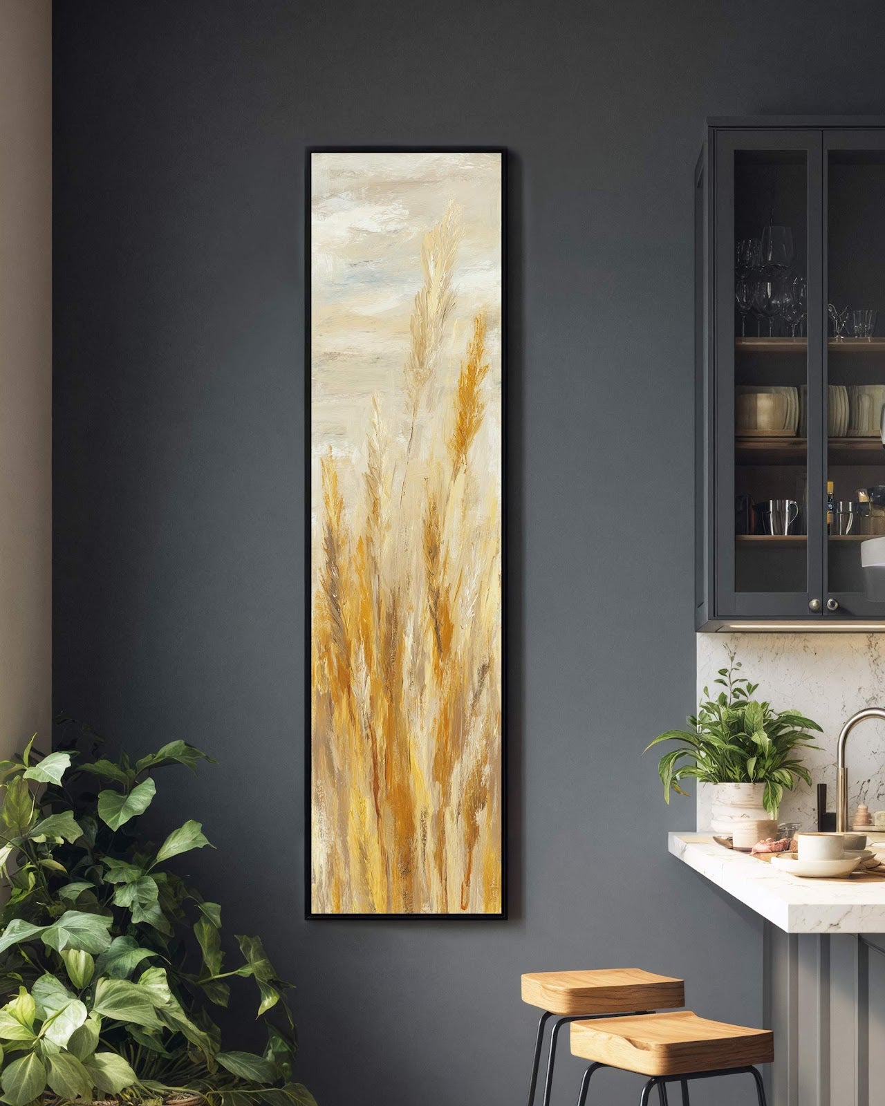 This vertical art print features pampas grass in a golden and beige impressionistic style, hanging in a black floater frame on a charcoal painted wall beside a marble kitchen countertop.