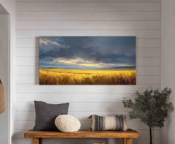 This horizontal canvas wall art features a dramatic landscape of a golden wheat field under a stormy, dramatic sky. It is displayed above a rustic wooden bench with decorative pillows.