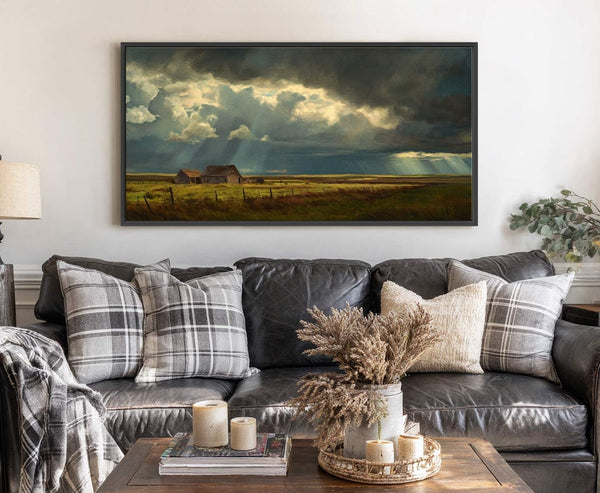 This horizontal canvas print wall art features a dramatic landscape of a rustic barn under stormy, sun-drenched skies, painted in a realistic style with a dark and moody palette. It.
